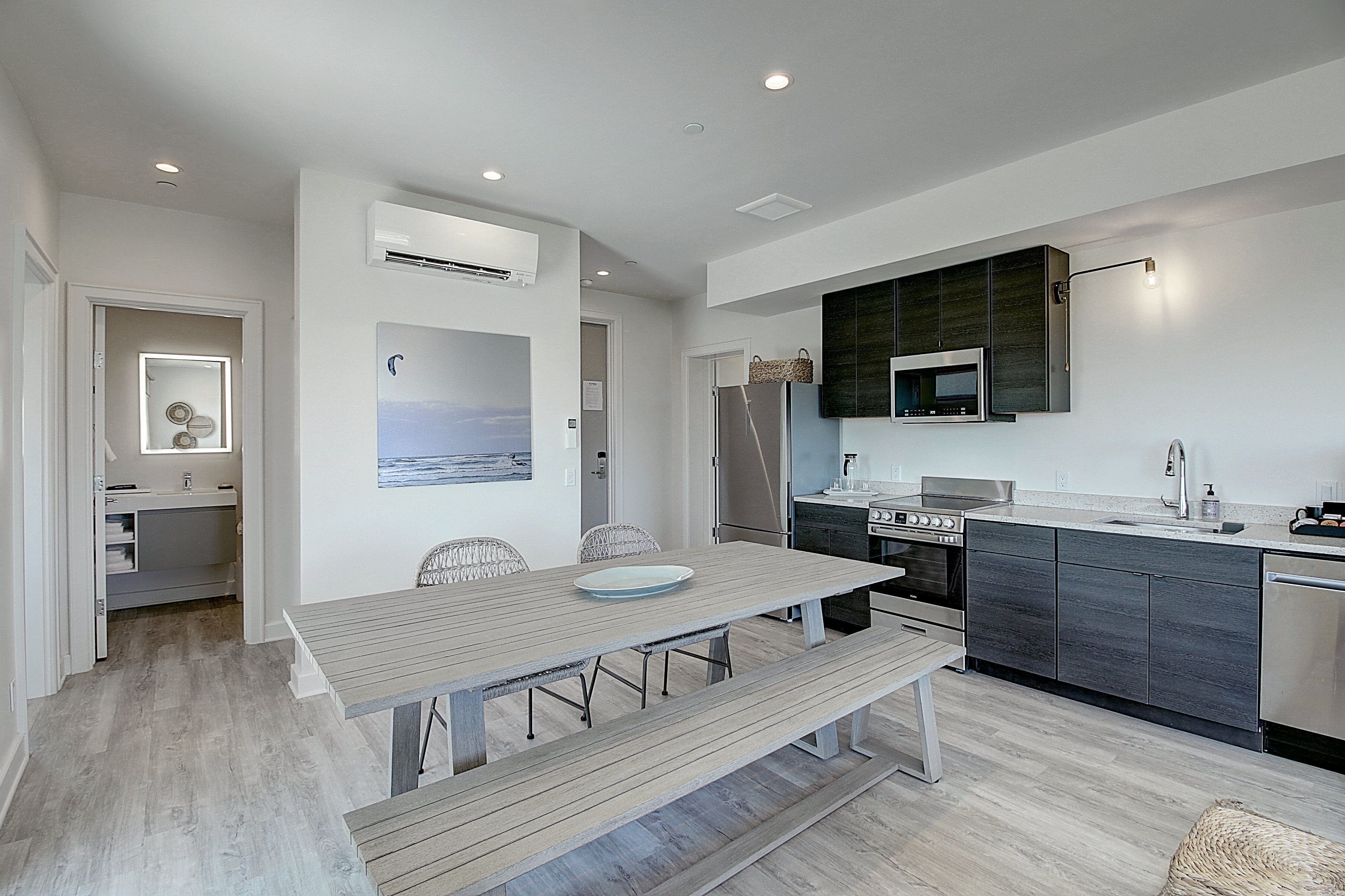 A modern kitchen with a built-in microwave, stove, and sink. There is a dining table with chairs and a bench.