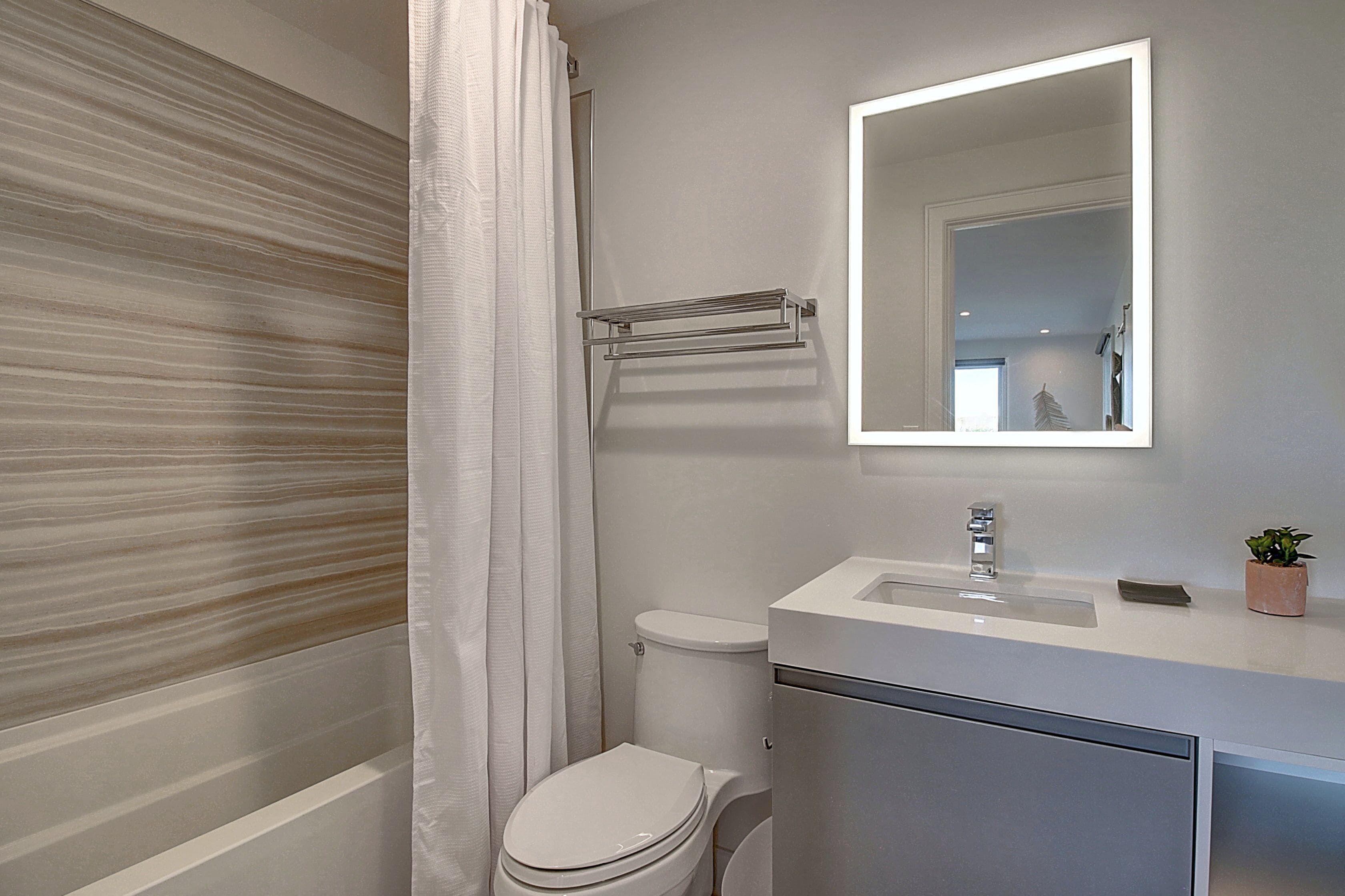 A bathroom with a toilet, a sink, a mirror, and a towel rack.
