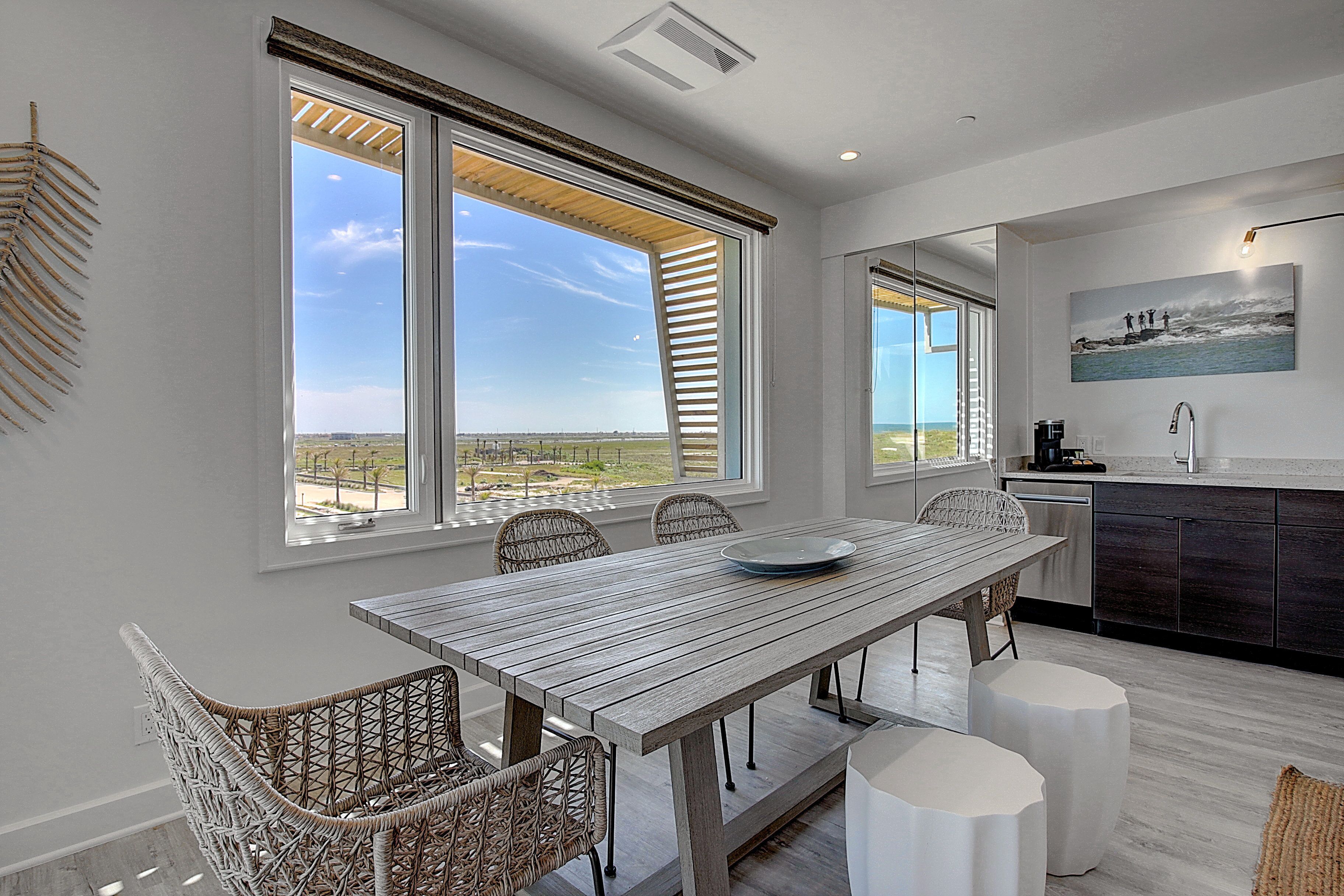 Una cocina moderna con una isla grande, muebles blancos y vistas al exterior.