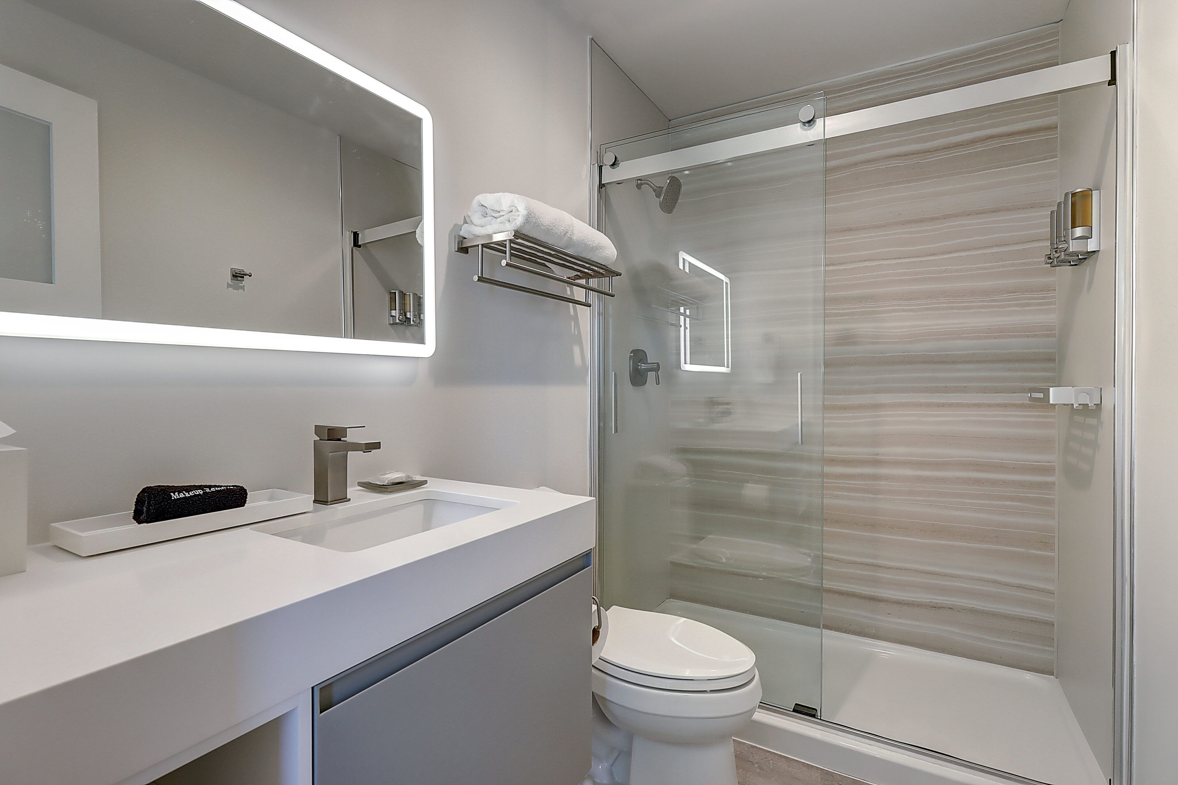 Une salle de bain moderne avec une douche à parois de verre, un lavabo blanc et des toilettes.