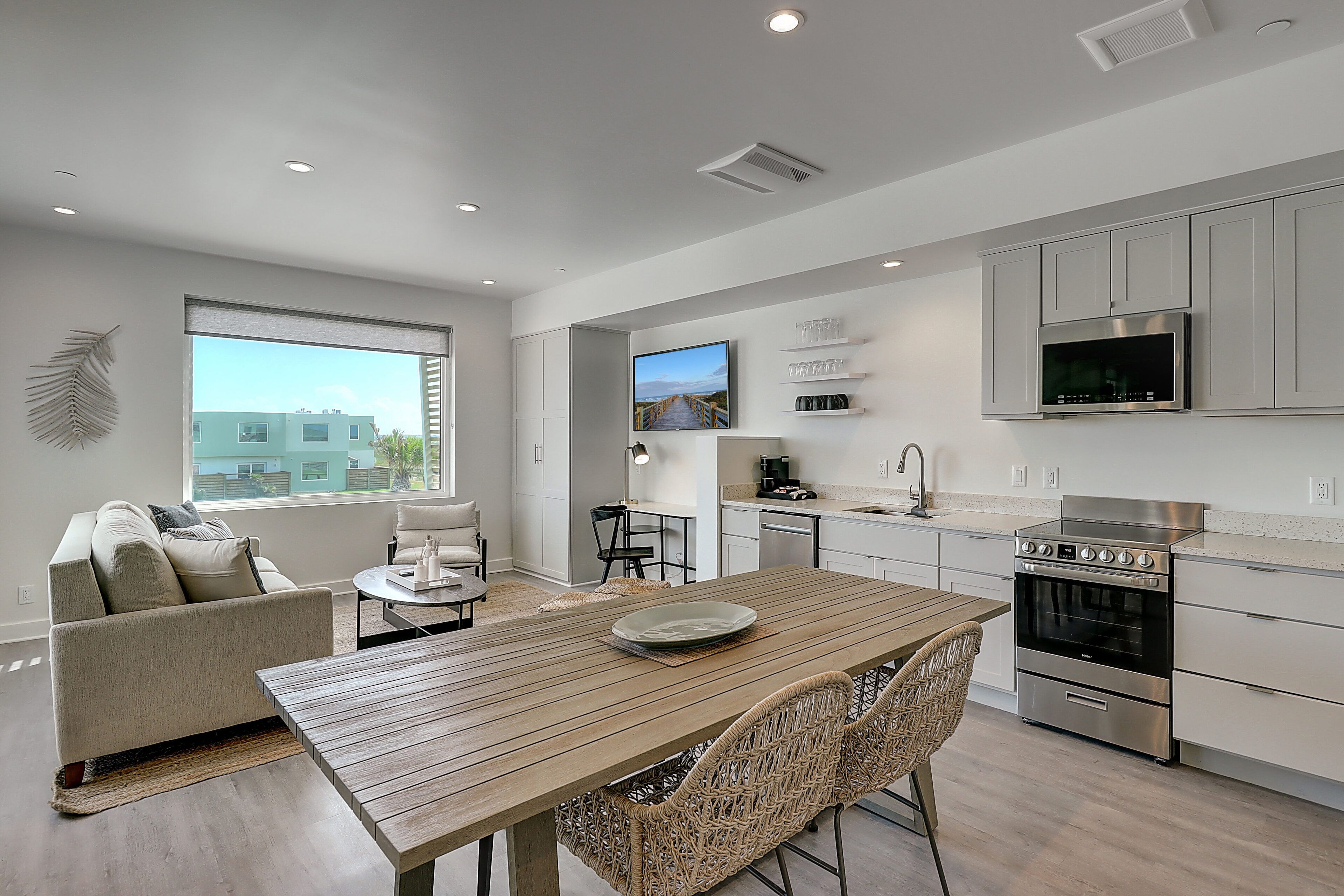A modern kitchen with a dining area, built-in appliances, and a large window offering a view of the city.