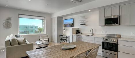 A modern kitchen with a dining area, built-in appliances, and a large window offering a view of the city.