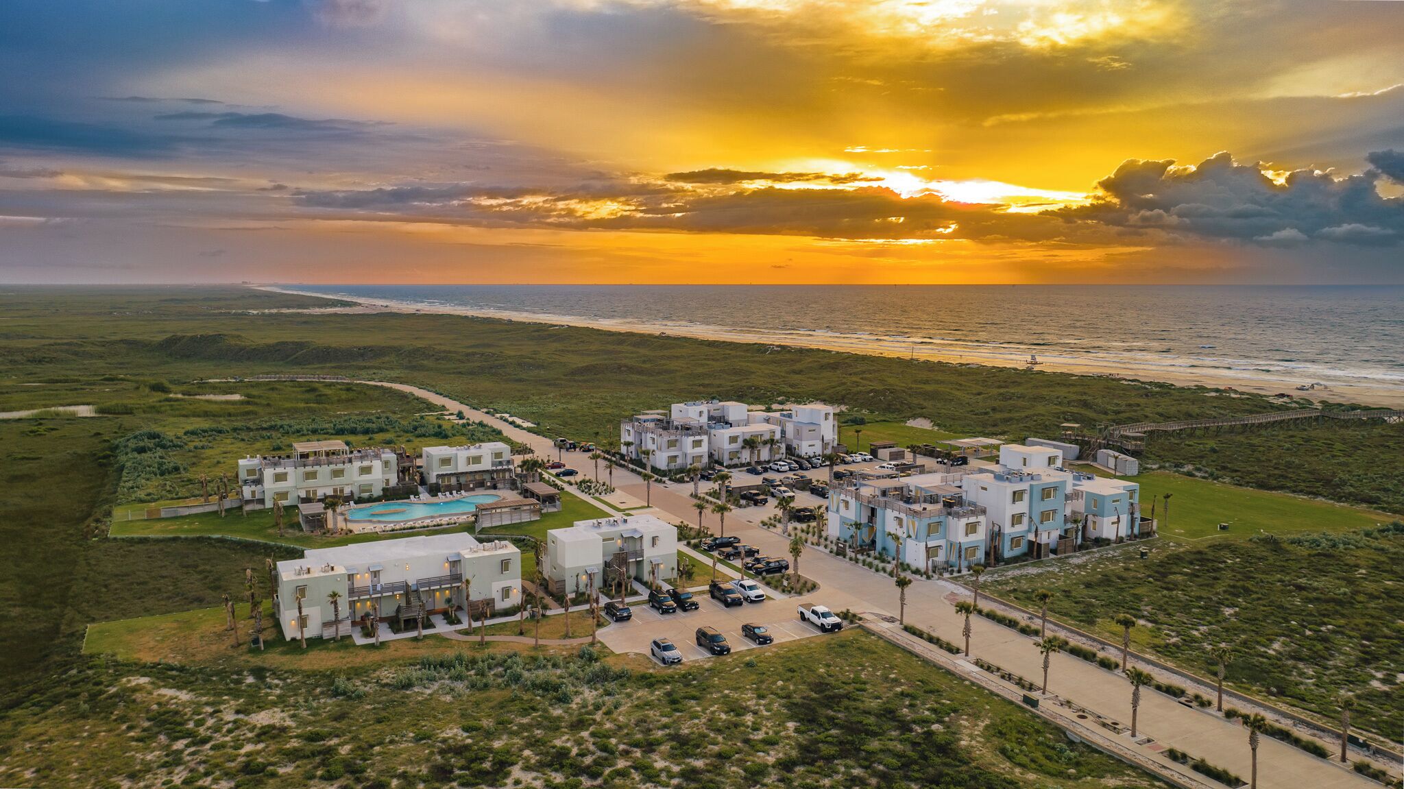 A coastal resort with multiple buildings, a swimming pool, and a beach view.