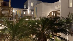 A modern building with a staircase and palm trees, under a night sky with a visible moon. - Lively Beach (Corpus Christi)