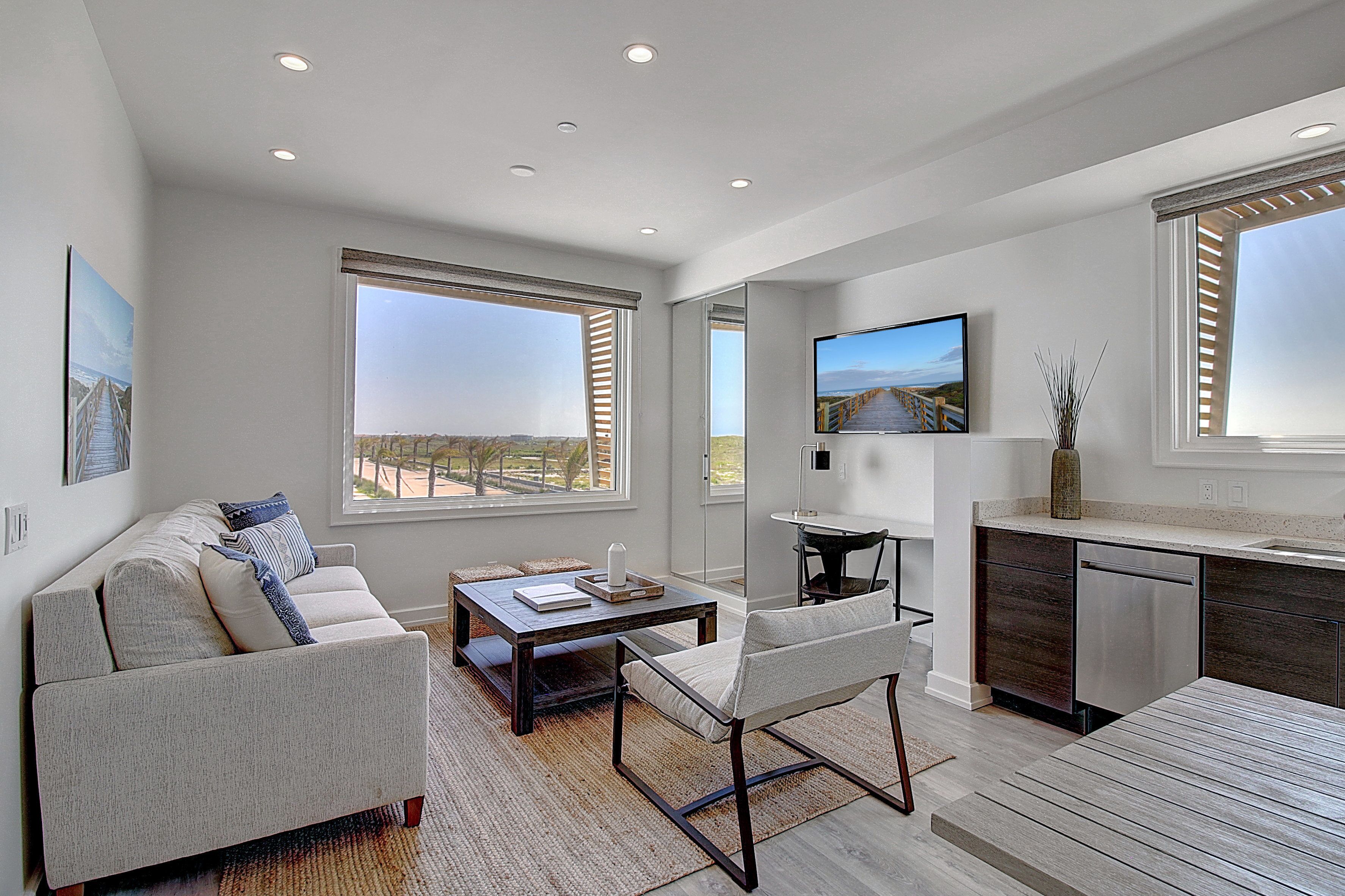 A modern living room with a sofa, coffee table, and a dining area.