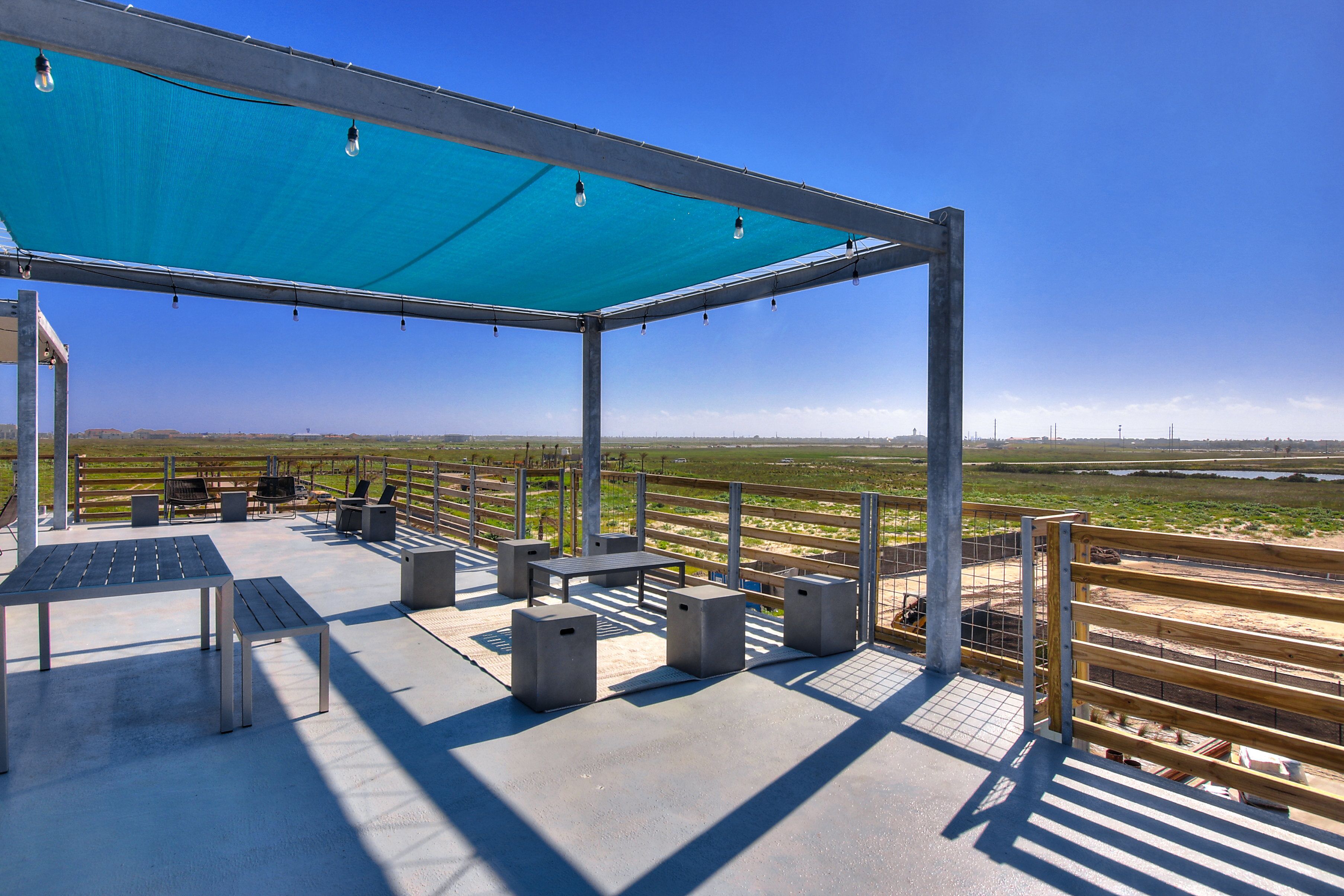 Eine Terrasse im Freien mit Tischen, Stühlen und einem schattigen Bereich.