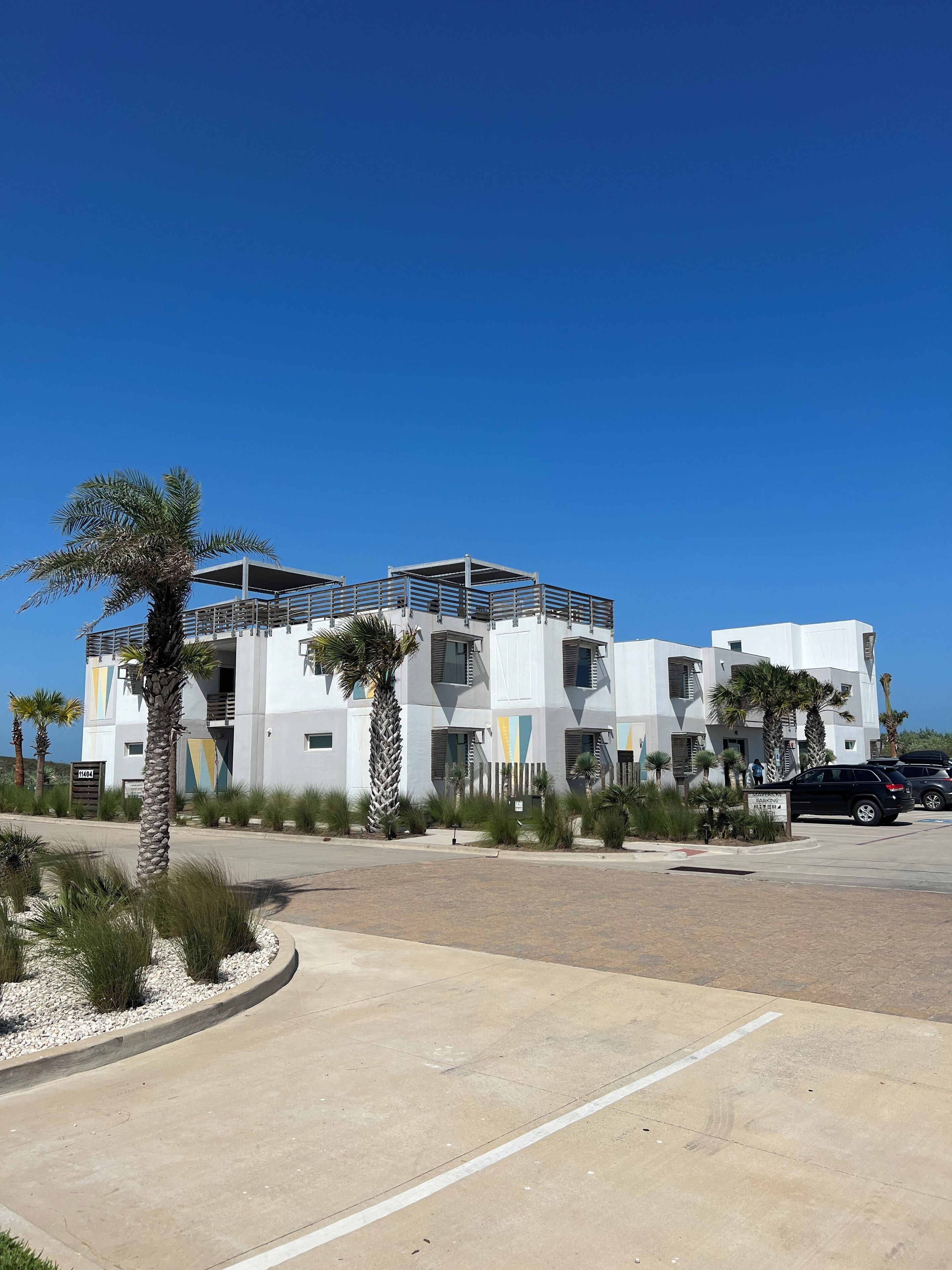 A modern multi-story building with a parking area in front.