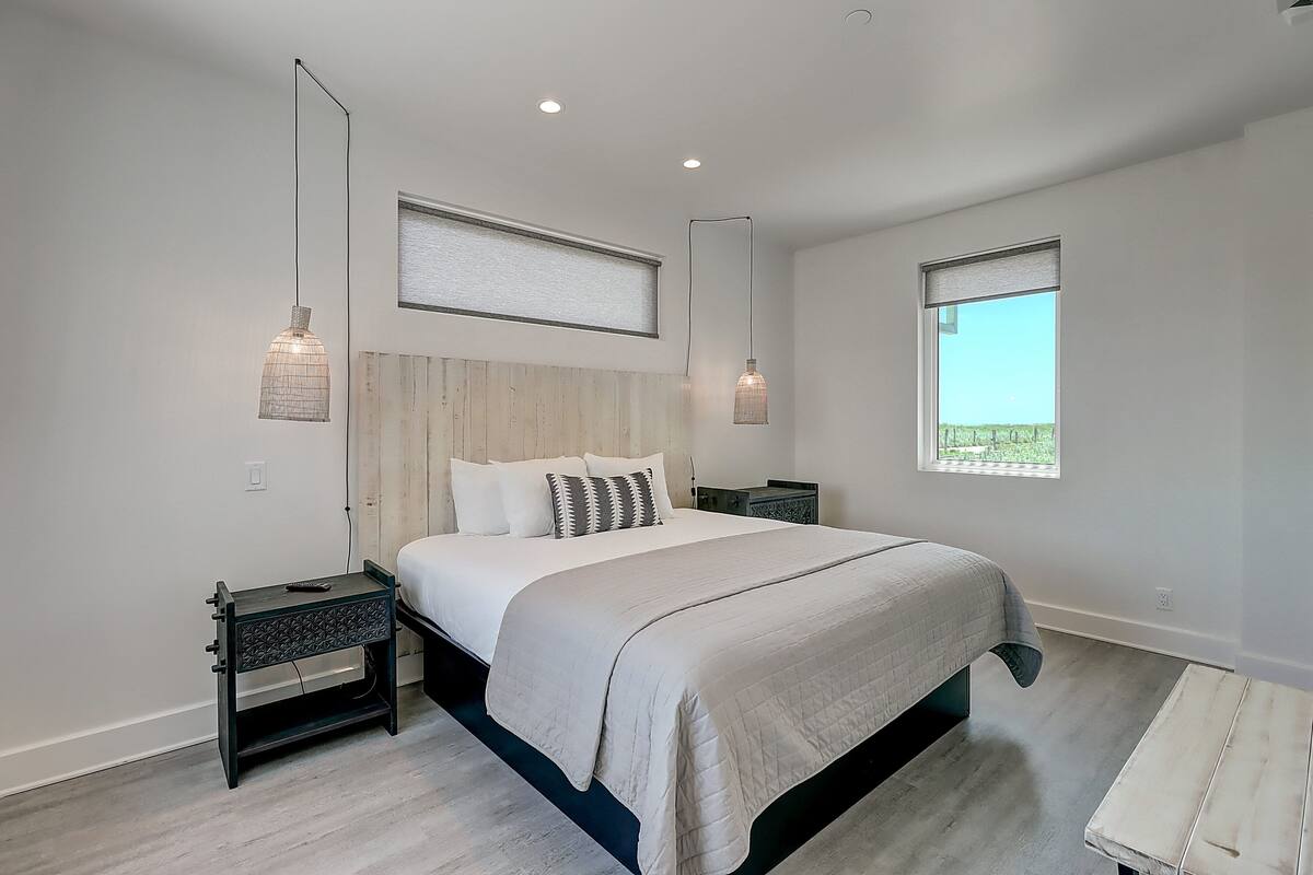 Un dormitorio moderno con una cama grande, dos mesitas de noche y lámparas colgantes.