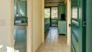 A hallway with a bathroom on the left, a dining area with a table and chairs in the center, and a green door on the right. - Nice apartment for 3 people with A/C, pool, WIFI, TV, terrace and pets allowed (Orosei)