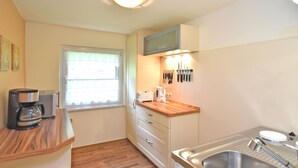 A compact kitchen with a wooden countertop, a built-in microwave, a coffee maker, and a sink. - Apartment in Saxony With Terrace (Crottendorf)