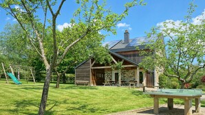 Een rustieke hut met een stenen fundering, houten gevel en een overdekt terras.