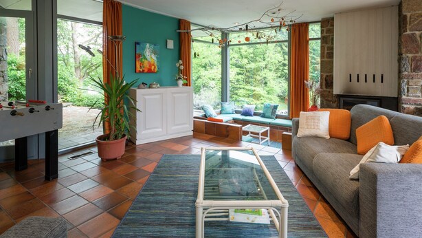 Una sala de estar acogedora con sofá, una mesita de centro y vistas al verdor exterior.