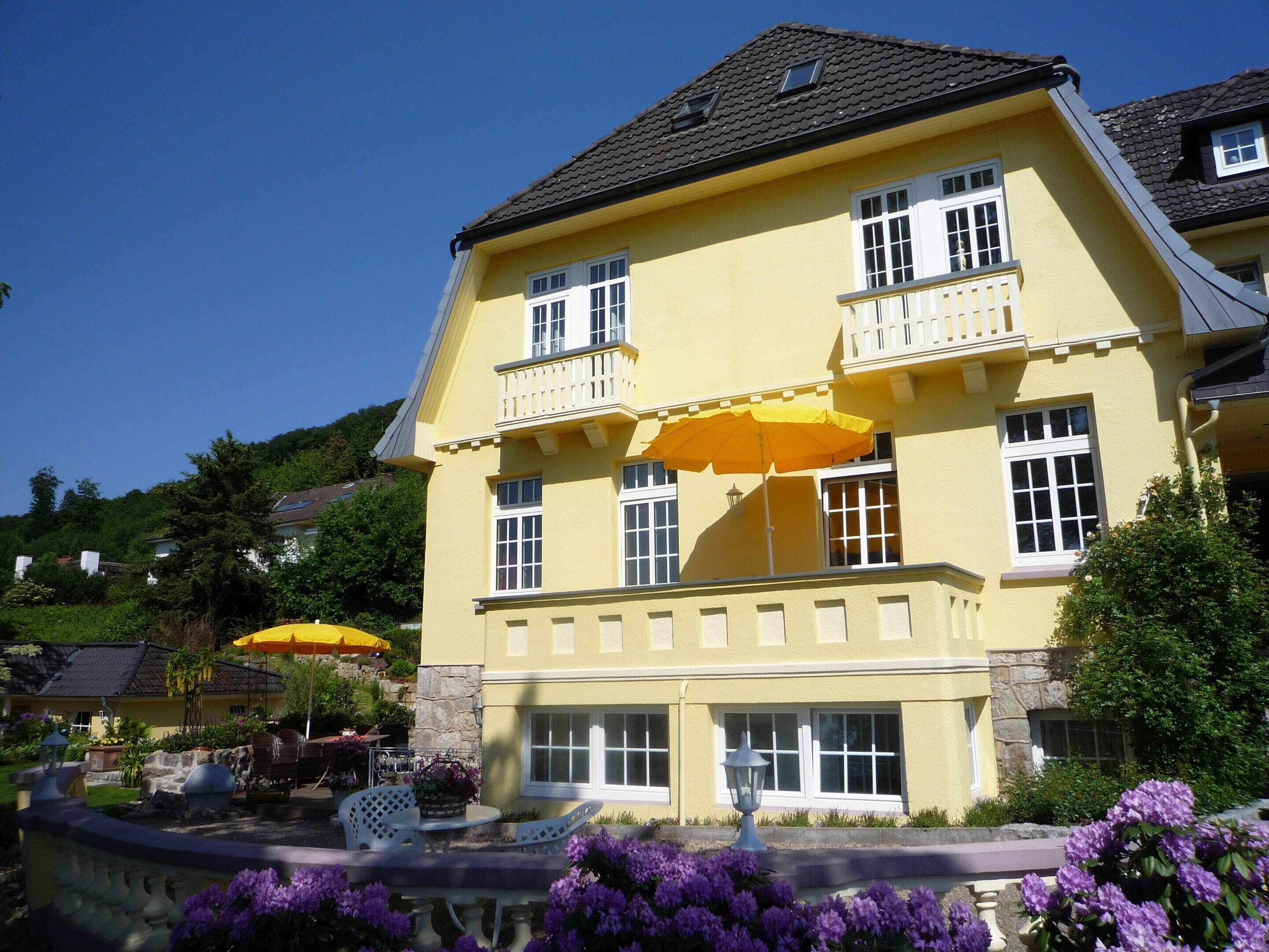 A two-story building with a yellow facade, multiple windows, and a balcony.