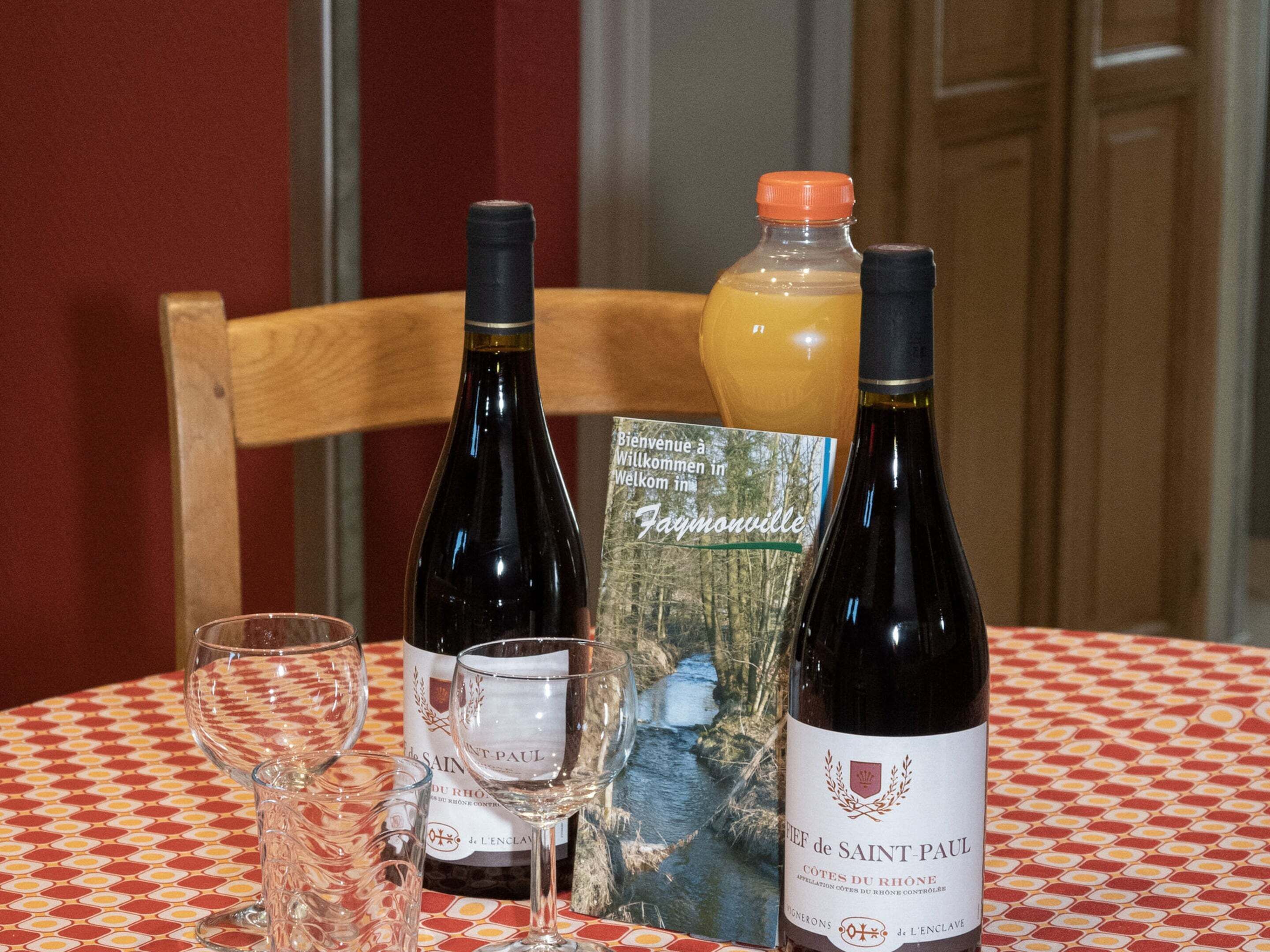 A table with two wine bottles, a glass, and a brochure.