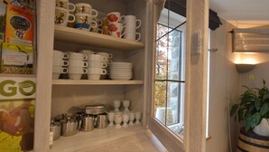 A kitchen with white cabinets, a window with a view of trees, and a plant on the right. - Holiday Home with Sauna, Garden, Terrace, BBQ & Fireplace (Waimes)