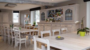 A spacious dining area with wooden tables and chairs, a large cabinet with various items, and a potted plant. - Holiday Home with Sauna, Garden, Terrace, BBQ & Fireplace (Waimes)