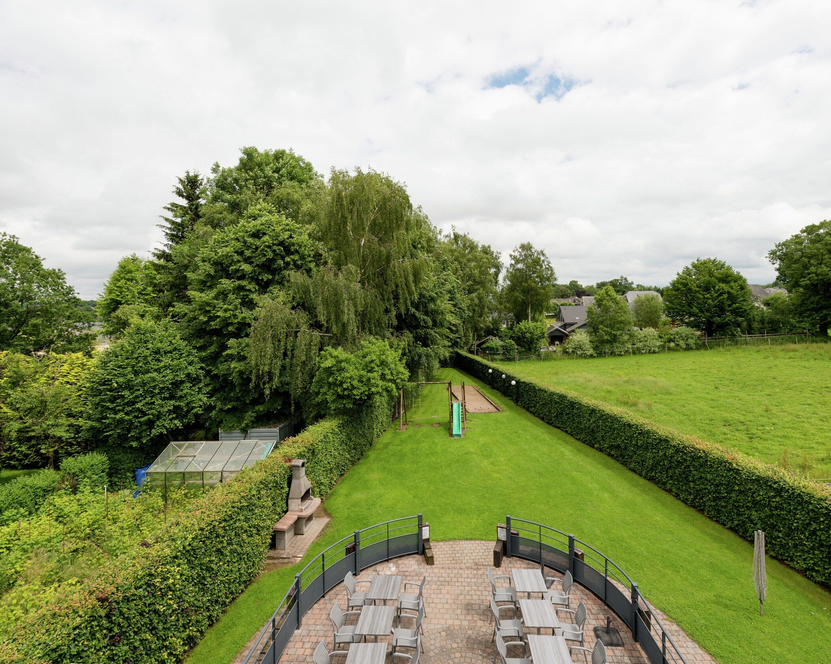 A patio area with outdoor seating and a view of a well-maintained lawn and trees.