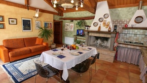 Una sala de estar acogedora con techo de madera, chimenea, mesa de comedor preparada para cuatro comensales y un sofá.
