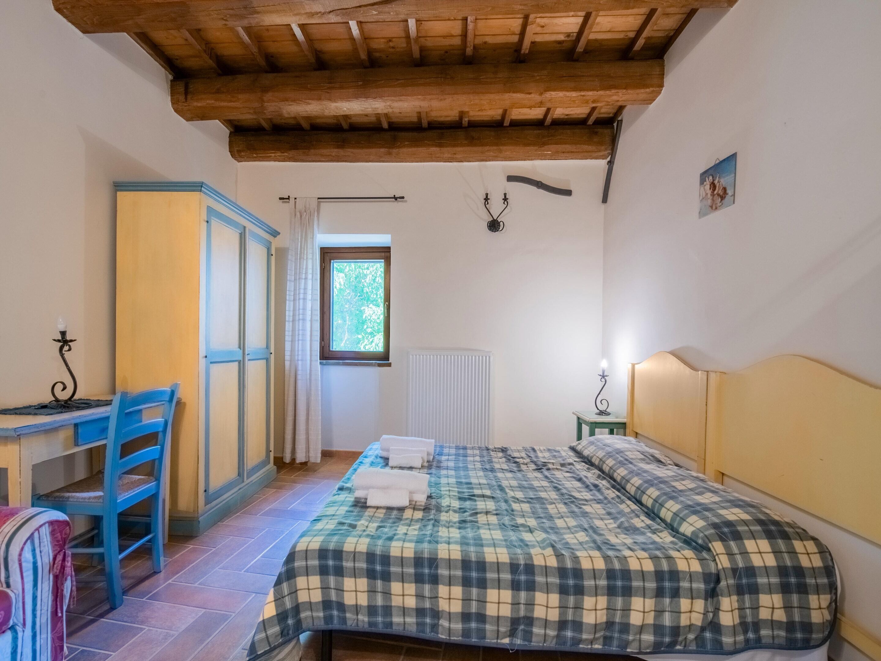 A bedroom with a bed, a desk, a chair, and a window.