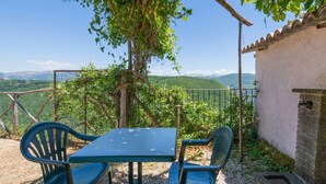 A table and chairs under a tree with a view of mountains. - Belvilla by OYO Fonni Blu (Sellano)