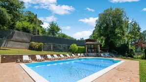A rectangular swimming pool with a tiled border, surrounded by a brick patio. - Belvilla by OYO Fonni Blu (Sellano)
