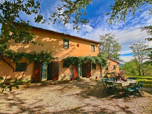 A rustic villa with a gravel patio, outdoor seating, and a garden.