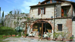 A rustic stone building with a patio area, outdoor seating, and potted plants. - Elegant Villa in Tuscany (Rapolano Terme)