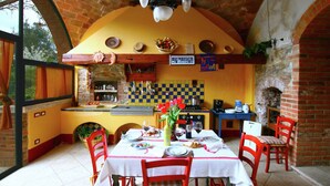 A dining area with a brick fireplace, a tiled backsplash, and a checkered wall pattern. - Elegant Villa in Tuscany (Rapolano Terme)
