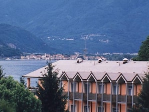 Un immeuble à plusieurs étages, doté d’un toit plat, situé près d’une étendue d’eau, avec des montagnes en arrière-plan.