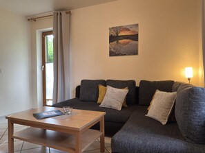 A living room with a sofa, a coffee table, and a painting on the wall. - Gemutliches Ferienhaus mit Terrasse im Teutoburger Wald (Brakel)