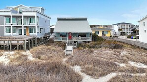 A beachfront property with a multi-story building, a wooden deck, and a sandy beach area.