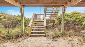 A wooden staircase leading to a covered area with a clear view of the sky and surrounding vegetation.