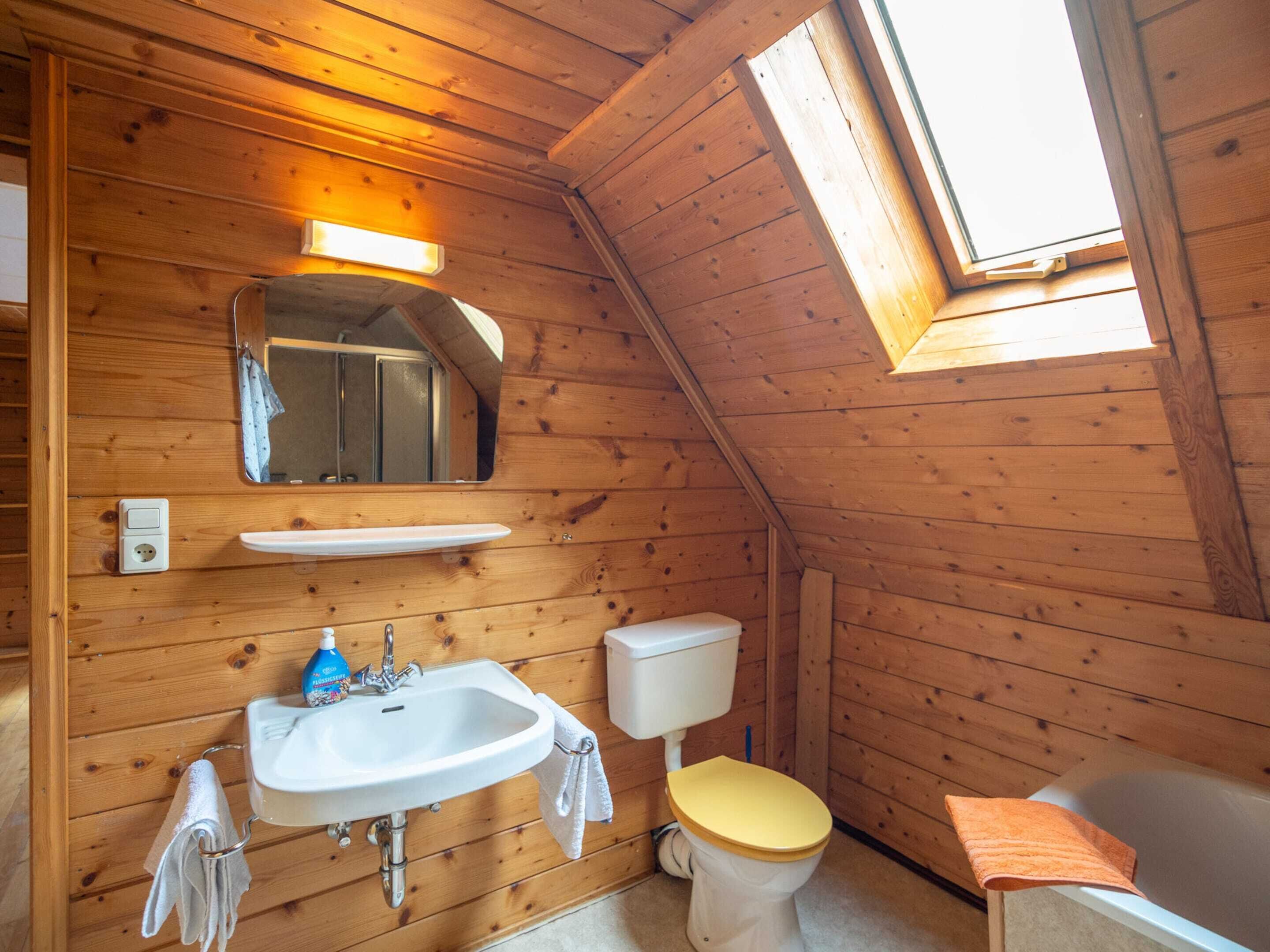 A compact wooden cabin bathroom with a sink, toilet, and bathtub.