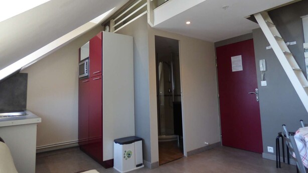 A modern kitchen with a microwave, a small trash bin, and a glass-enclosed shower.