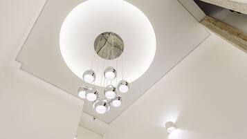 Teto moderno com luminária circular e várias luzes pendentes.