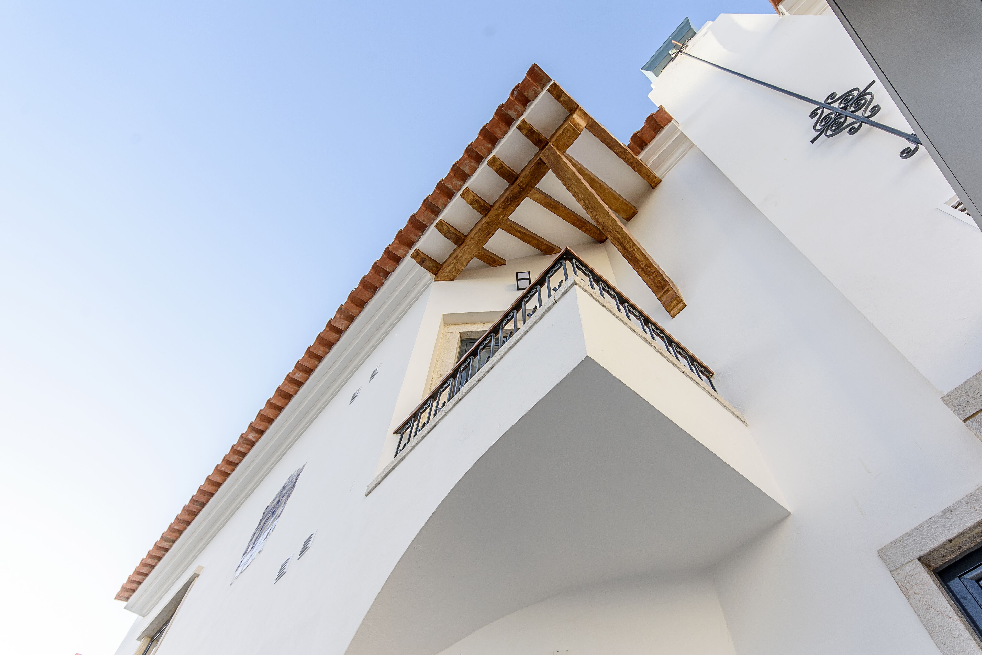 A building with a white facade, a wooden balcony, and a black railing.