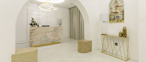 A modern reception area with a marble counter, a gold console table, and a mural on the wall.