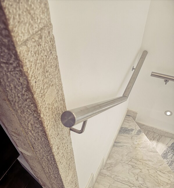 A corner of a room with a marble floor and a metal handrail against a textured wall. - Villa Mariazinha Charming Hotel (Portimão)