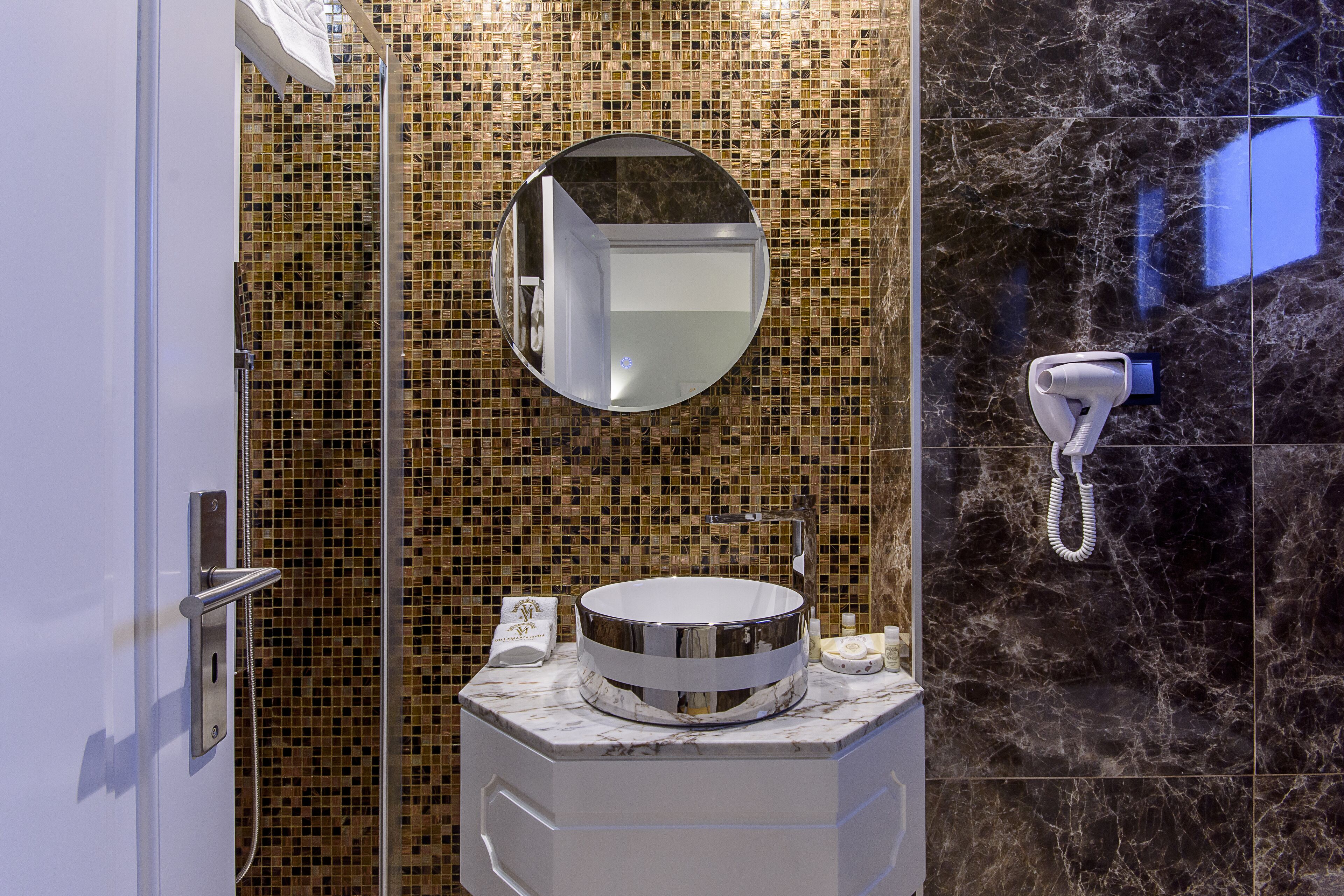 Un baño con un espejo redondo, un lavabo y una zona de ducha.
