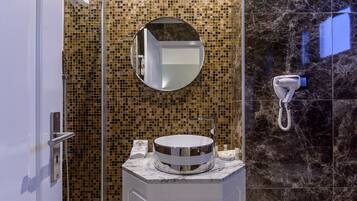 Un baño con un espejo redondo, un lavabo y una zona de ducha.