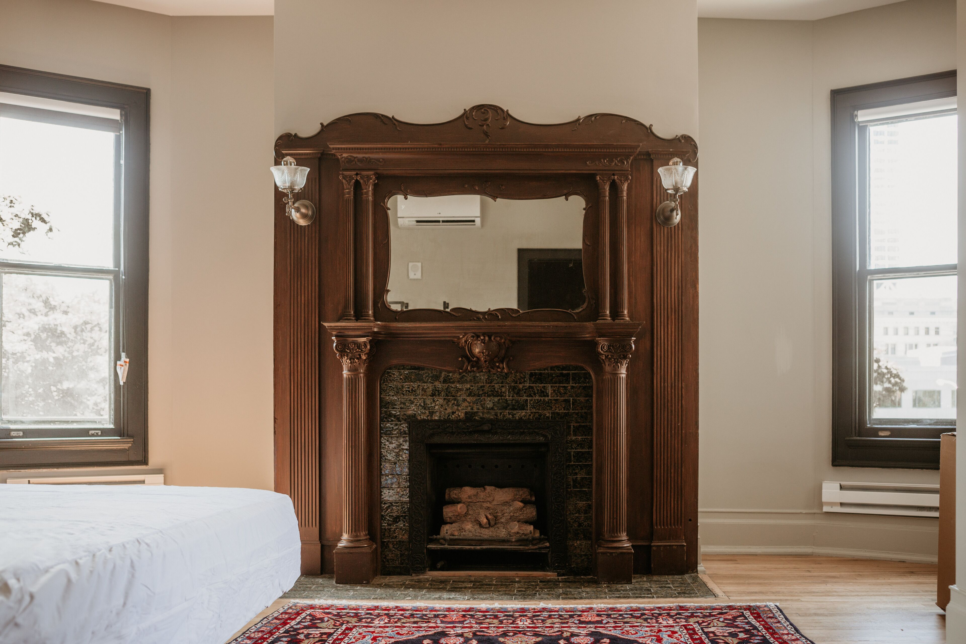 A room with a fireplace, a bed, and large windows.