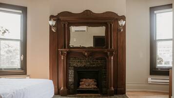 A room with a fireplace, a bed, and large windows.