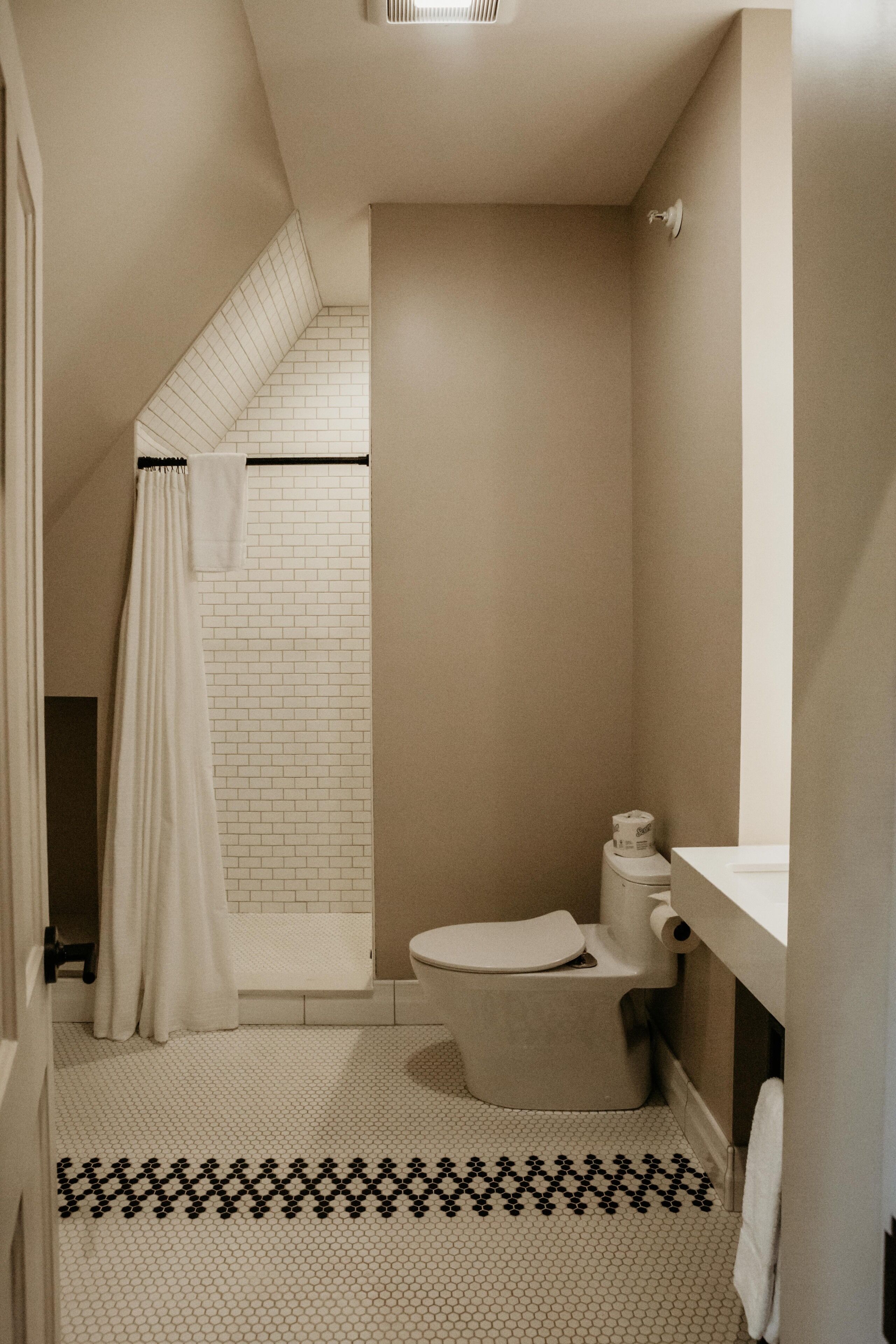 Ein Badezimmer mit Toilette, Duschvorhang und Fliesenboden.