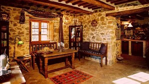 A rustic interior with stone walls, wooden beams, a wooden table, a bench, and a bookshelf. - Villa in Maremma With Private Pool & Views (Santa Fiora)
