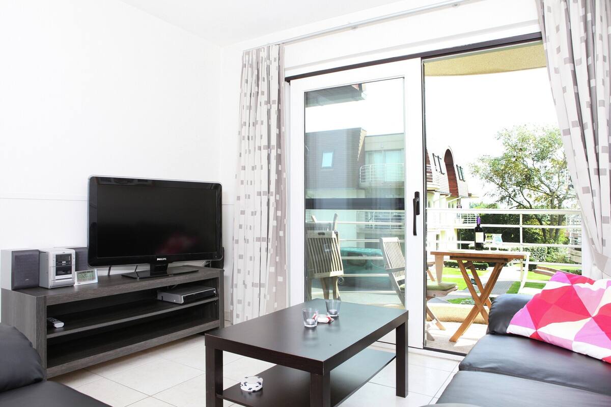 A modern living room with a flat-screen TV, a coffee table, and a sofa.