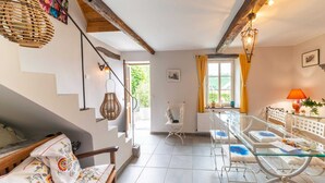 A modern living room with a staircase, a glass dining table, and a cozy seating area. - Charming Cottage in Anseremme With Fenced Garden (Dinant)
