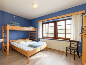 Habitación con literas, ventana, radiador y una silla.