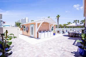Guests can enjoy an outdoor space with a table and chairs, surrounded by a low fence and adjacent to a swimming pool.