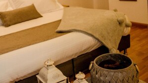 A neatly made bed with white linens and a green headboard, a bedside table with a white lamp, and a large woven basket on the floor. - Mumu by Bernalo Hotels (Guatapé)