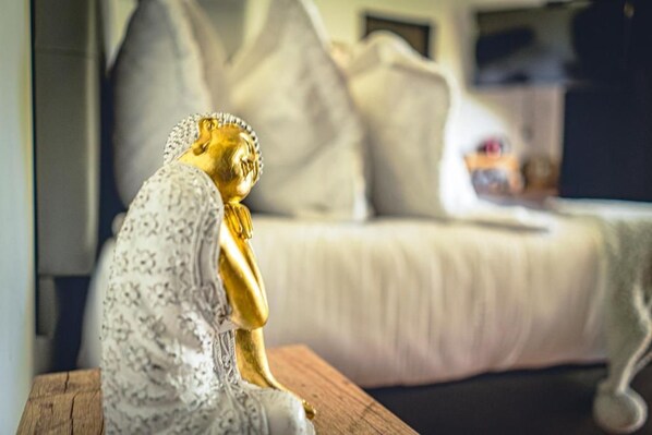 A room with a bed, pillows, and a decorative golden statue on a wooden surface. - Mumu by Bernalo Hotels (Guatapé)